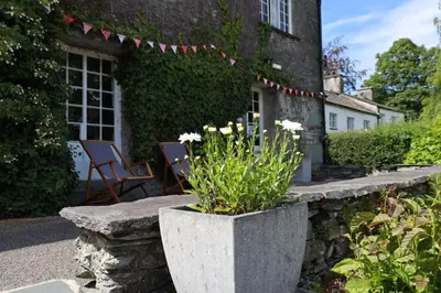 a stone planter with flowers in front of a house at Elterwater Hostel in Elterwater