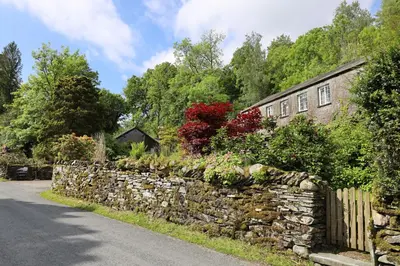 a stone retaining wall next to a house at Elterwater Hostel in Elterwater