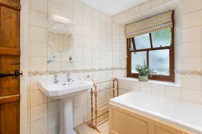 a bathroom with a sink and a tub and a mirror at Old Sawpit in Ambleside