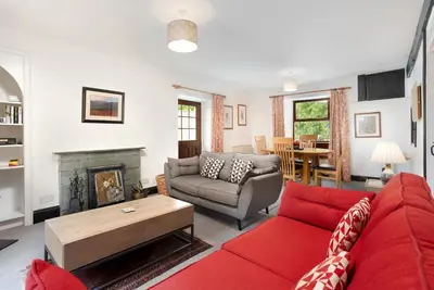 a living room with a red couch and a fireplace at Old Sawpit in Ambleside