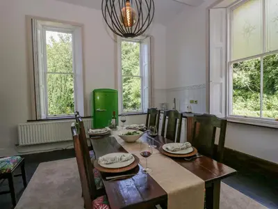 a dining room with a table and chairs and windows at The Residence in Cleator