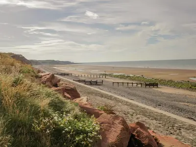 a sandy beach with benches and the ocean at The Residence in Cleator