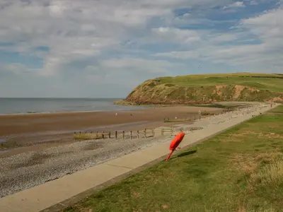 a beach with a red umbrella on the side of it at The Residence in Cleator