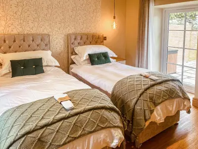 a bedroom with two beds and a window at Bumblebee Cottage-Uk39918 in Ballakinnag