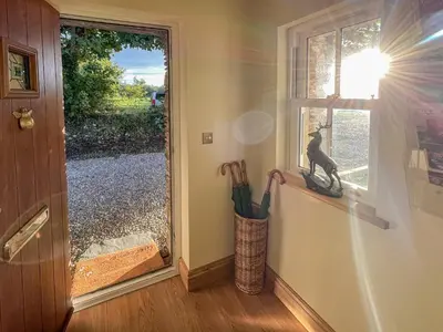 a window with a statue of a dog on a window sill at Bumblebee Cottage-Uk39918 in Ballakinnag