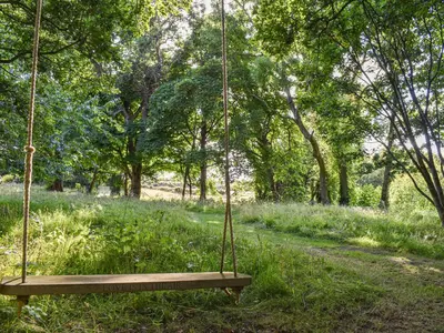 a swing in a park with trees and grass at Bumblebee Cottage-Uk39918 in Ballakinnag