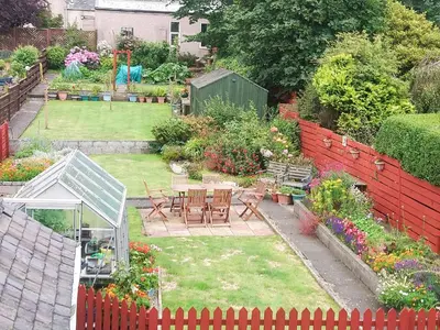a garden with a table and chairs and flowers at Fiddlers Rest in Ballantrae