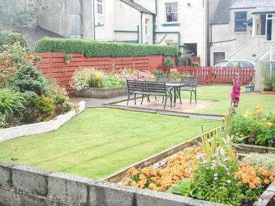 a garden with two benches and a table and flowers at Fiddlers Rest in Ballantrae