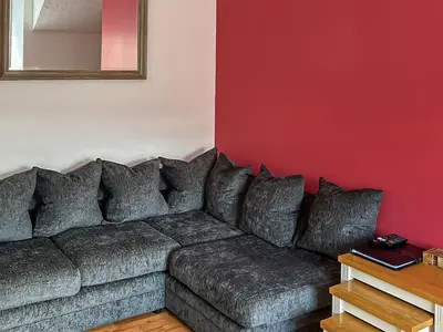a living room with a gray couch against a red wall at Fiddlers Rest in Ballantrae