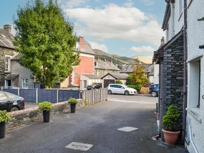 a street in a small town with cars parked at Buttermere Apartment in Keswick
