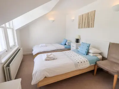 a bedroom with two beds and a chair at Fell Sweep in Keswick
