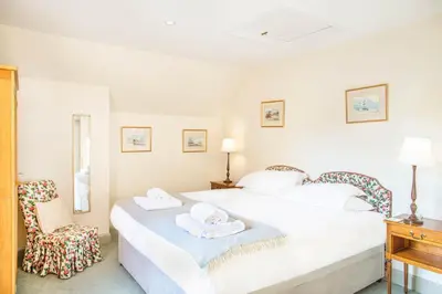 a white bedroom with a bed and a chair at The Stables in Castle Douglas