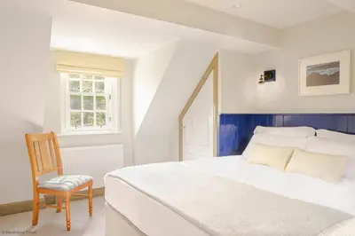a bedroom with a white bed and a chair at Culdoach in Castle Douglas