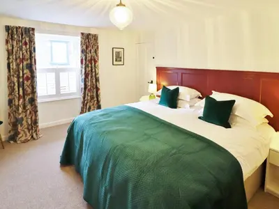 a bedroom with a large bed with green and white sheets at Union Street in Kirkcudbright