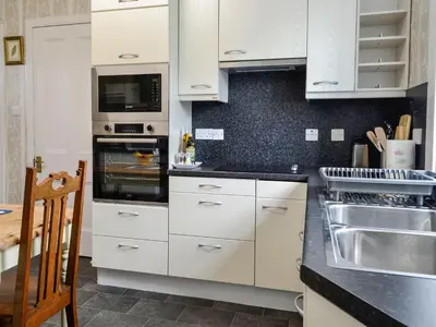 a kitchen with white cabinets and a stove top oven at Craigvar House in Castle Douglas