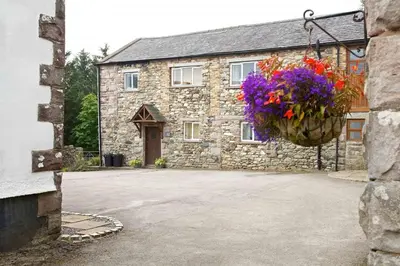 a stone house with a hanging basket of flowers at Cragside Cottage in Troutbeck