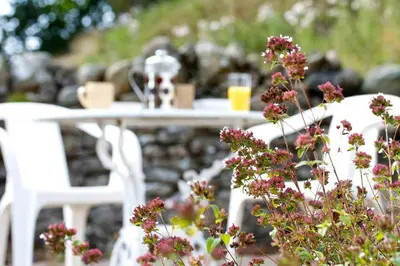 a white table with white chairs and flowers at Cragside Cottage in Troutbeck