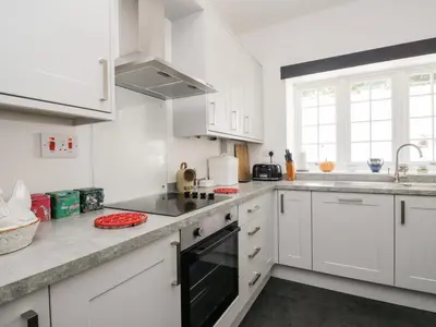 a white kitchen with white cabinets and a sink at Stables Cottage in Langholm