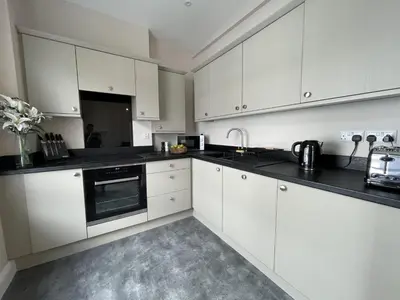 a kitchen with white cabinets and black counter tops at Grisedale Pike in Keswick