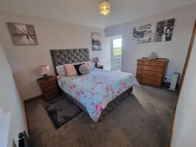 a bedroom with a bed and a dresser and a mirror at The Auld Byre - by the Beach in Dumfries