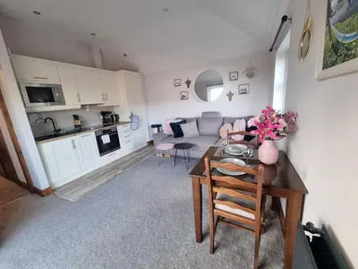 a small living room with a table and a kitchen at The Auld Byre - by the Beach in Dumfries