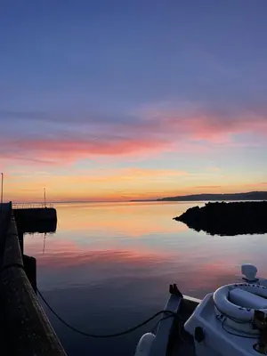 a boat on a body of water at sunset at Immaculate 2-Bed Lodge in Monreith in Newton Stewart