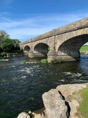 a stone bridge with three arches over a river at Luxury Cottage, views of the Lakes with Hot Tub in Cockermouth