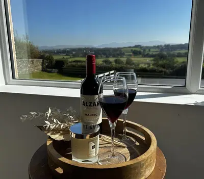 a bottle of wine and two glasses on a table at Luxury Cottage, views of the Lakes with Hot Tub in Cockermouth