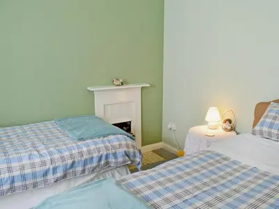 a bedroom with two beds and a fireplace at Gardener's Cottage in Palnure