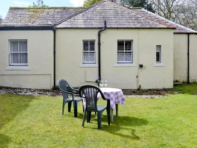 two chairs and a table in front of a house at Gardener's Cottage in Palnure
