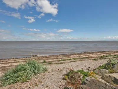 a sandy beach with the ocean in the background at Coastguard's Cottage in Carsethorn