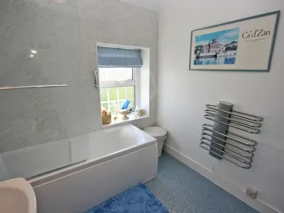 a white bathroom with a tub and a window at Coastguard's Cottage in Carsethorn