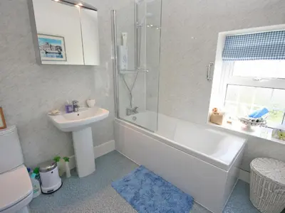 a bathroom with a white tub and a sink at Coastguard's Cottage in Carsethorn