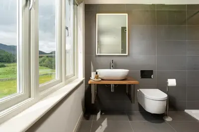 a bathroom with a sink and a toilet and a mirror at Lowfield House in Ambleside