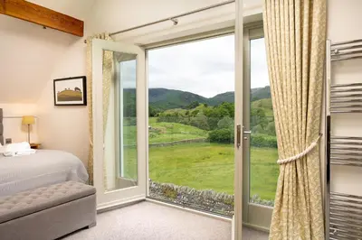 a bedroom with a bed and a large window at Lowfield House in Ambleside