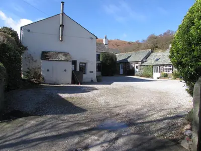 a large white building with a garage in a driveway at Cottage 1, Old Farmhouse Mews in Braithwaite