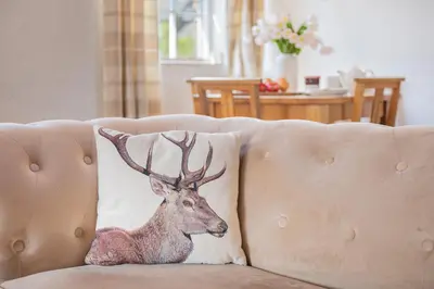 a cushion with a deer on a couch at Cottage 1, Old Farmhouse Mews in Braithwaite