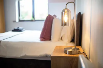 a bedroom with a bed and a lamp on a table at Maltings House Cosy and Stylish 2 bedroom flat near the city centre with free parking and ensuite rooms in Carlisle