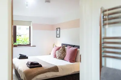 a bedroom with a bed with pink pillows at Maltings House Cosy and Stylish 2 bedroom flat near the city centre with free parking and ensuite rooms in Carlisle