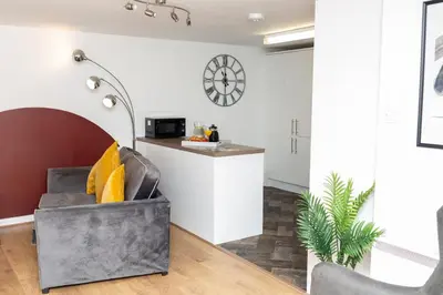 a living room with a chair and a counter at Maltings House Cosy and Stylish 2 bedroom flat near the city centre with free parking and ensuite rooms in Carlisle