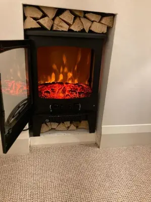 a fireplace with a fire inside of it at Marni’s Cottage - Rural location & fell views in Frizington