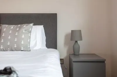 a bed with a pillow and a lamp on a nightstand at West Sands - Donnini Apartments in Ayr