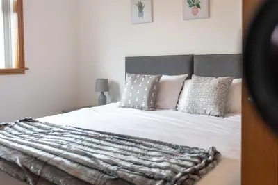 a bedroom with a bed with white sheets and pillows at West Sands - Donnini Apartments in Ayr