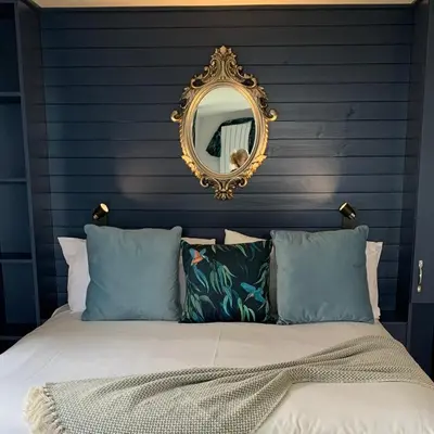 a bed with a mirror on a blue wall at Bothy Farm Stay Sleeps 2 HotTub and Pool Table Children Welcome Ayrshire Rural Retreats in Newmilns