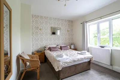 a bedroom with a bed and a chair and a window at Dalegarth House Portinscale in Keswick