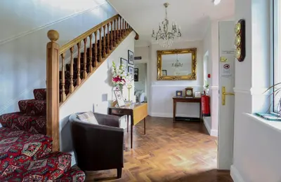 a living room with a staircase and a chair at Dalegarth House Portinscale in Keswick