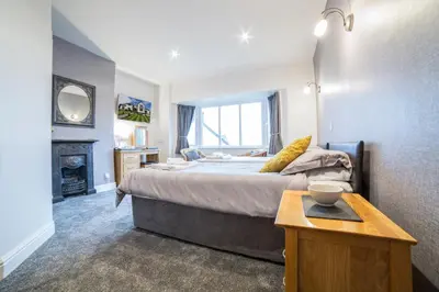 a bedroom with a large bed and a fireplace at Dalegarth House Portinscale in Keswick