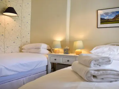 a bedroom with two beds and a table with lamps at Hey Down in Keswick