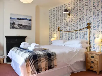 a bedroom with a bed with white sheets and a fireplace at Hey Down in Keswick