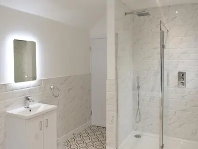 a white bathroom with a shower and a sink at Helvellyn House in Keswick